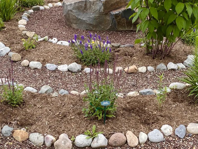 Fresh mulch laid through stone-edged garden beds around planted perennials